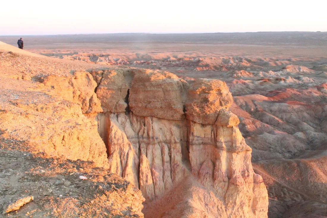 Pale badlands with a figure on the rim for scale
