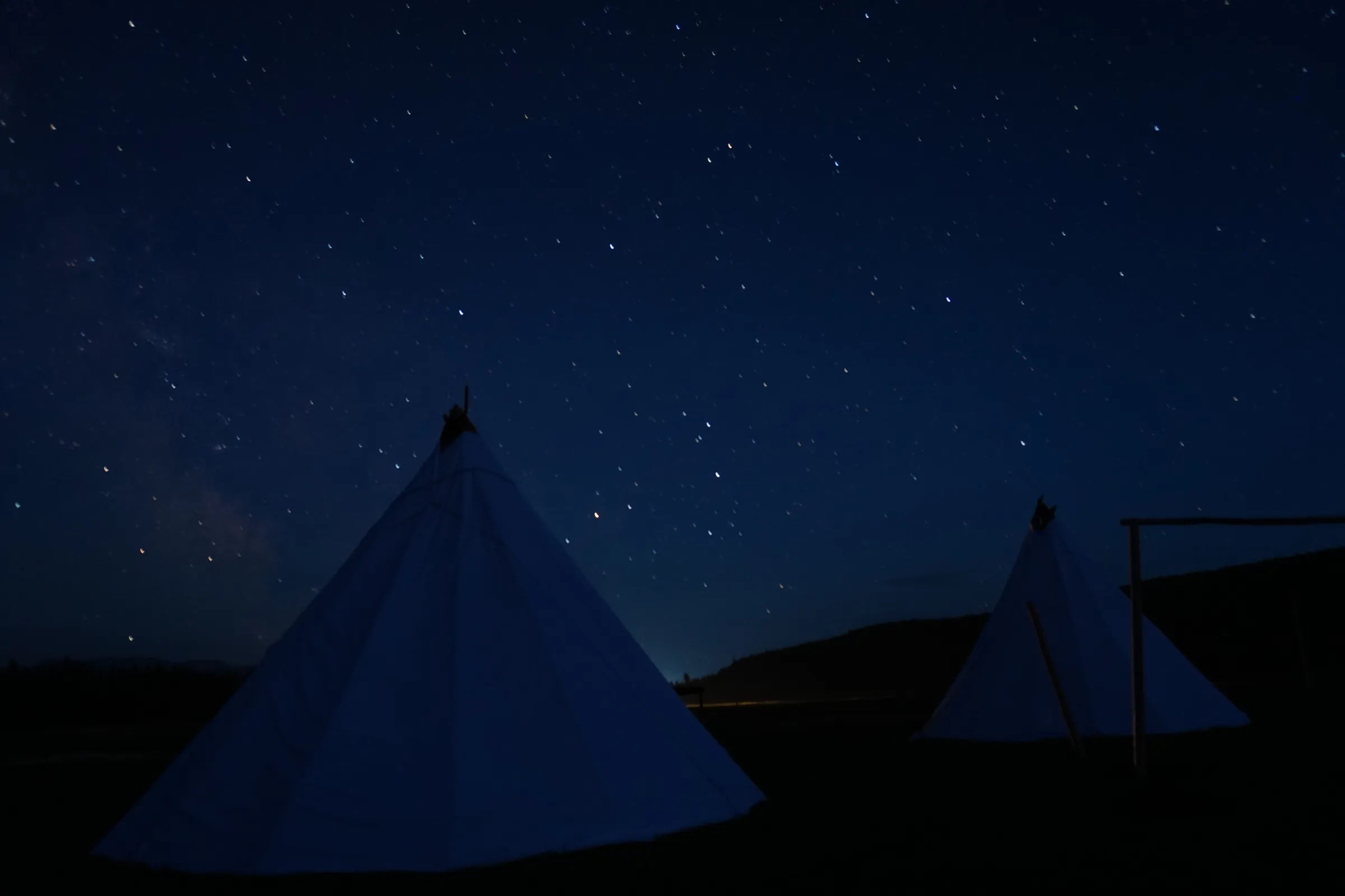 Two canvas teepees standing under a night sky full of stars