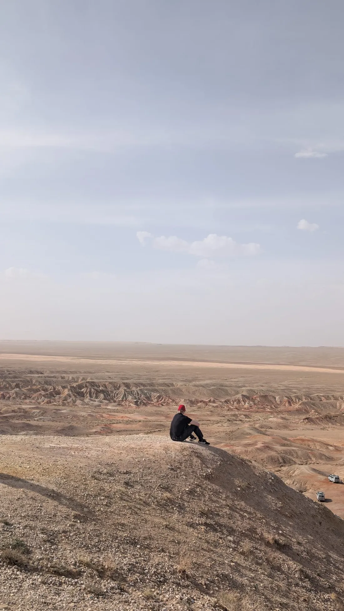 A figure seated above a hazy desert