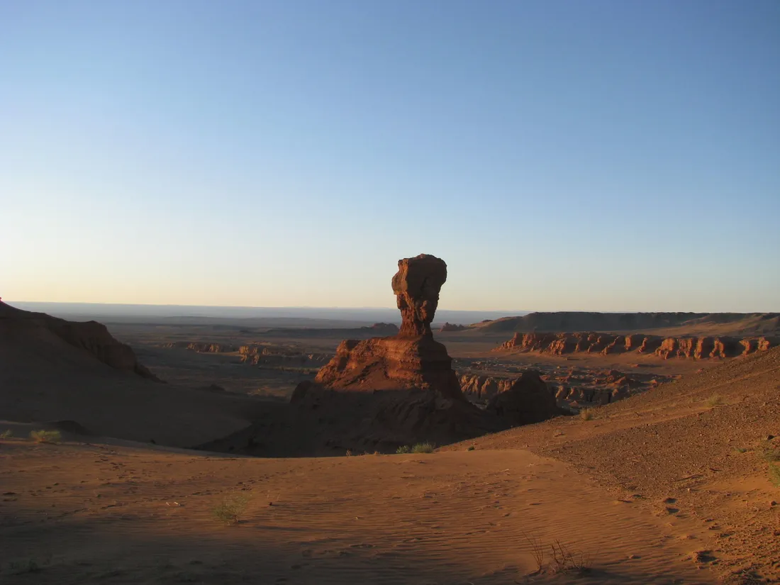 A lone sandstone pillar above the badlands in the evening light