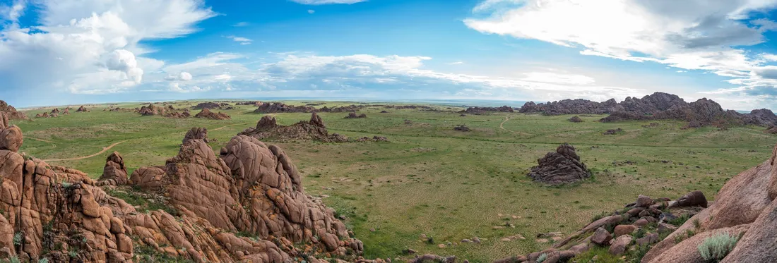 Granite outcrops scattered across green steppe
