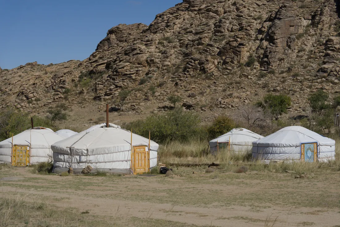 White gers of the research camp below a rocky hillside