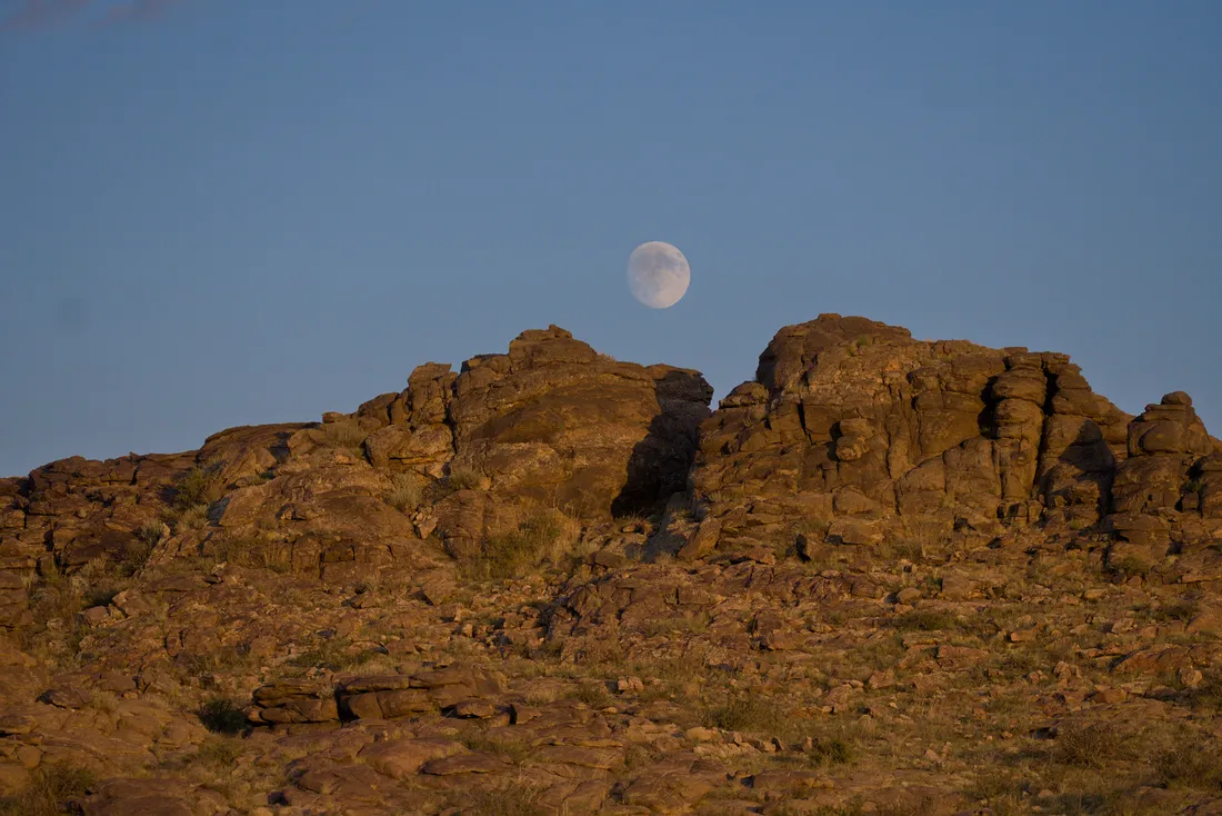 The moon rising over a granite outcrop in the last light