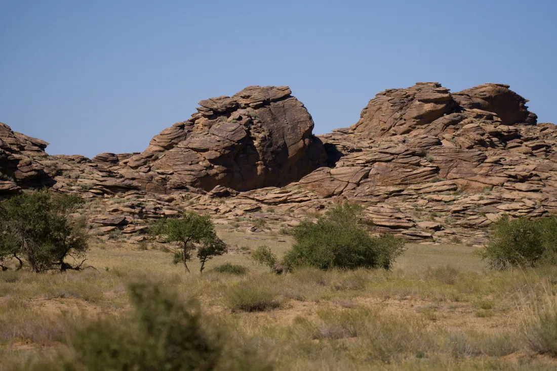 Weathered granite outcrops rising above scrub and steppe grass