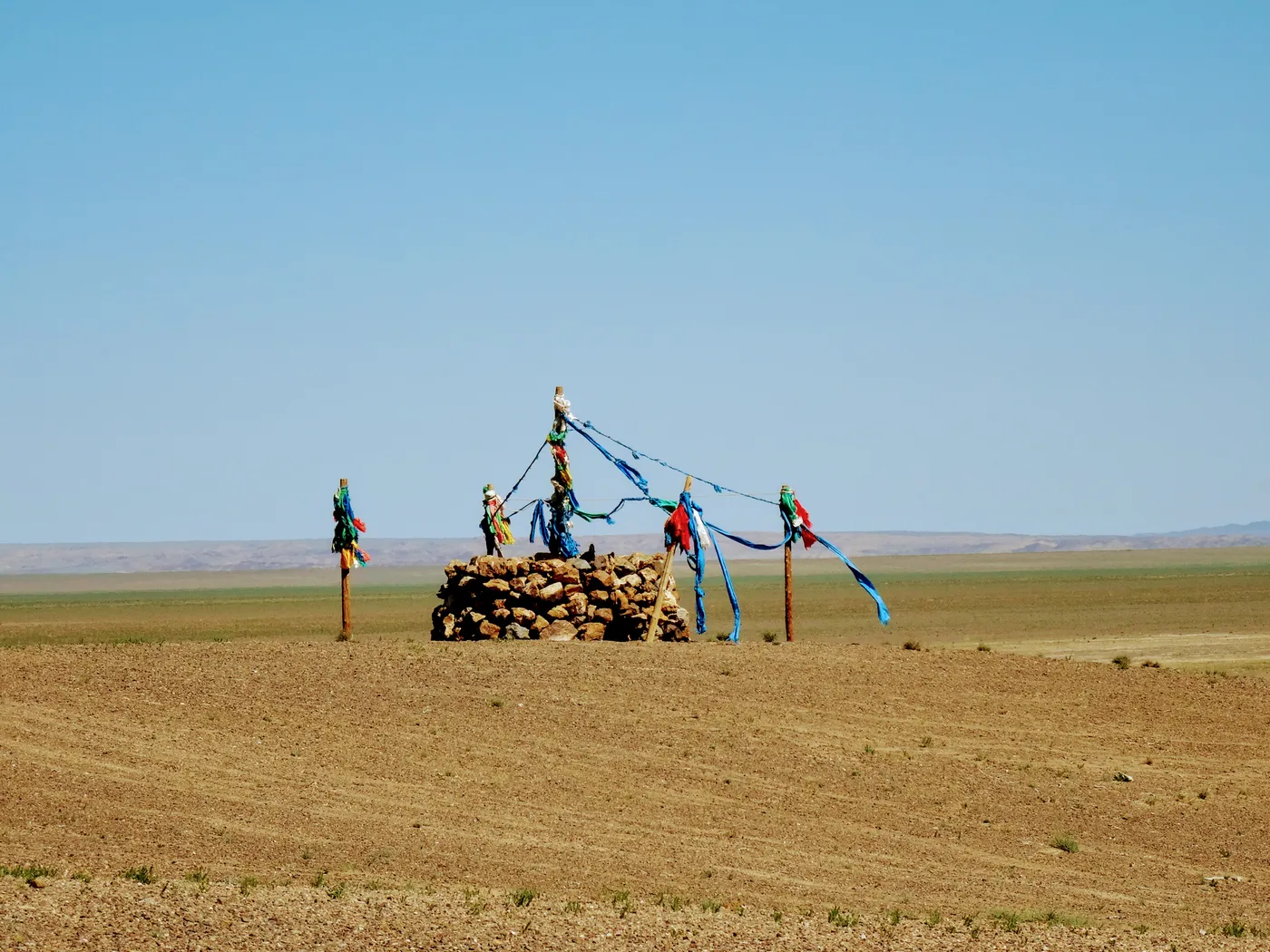 An ovoo strung with prayer flags on a bare plain
