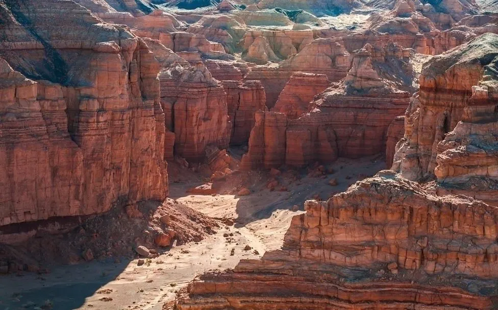 Layered red sandstone walls above a dry canyon floor