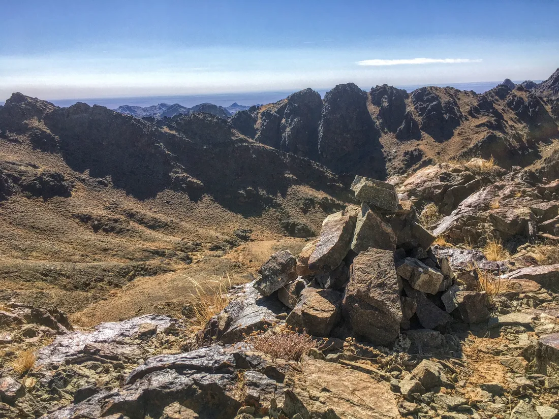 A stone cairn on a summit, with the ridges of the Tost Mountains stretching to the horizon