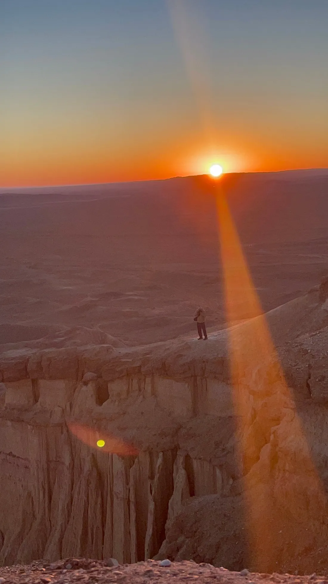 Sunrise over the badlands, with a distant figure on the rim