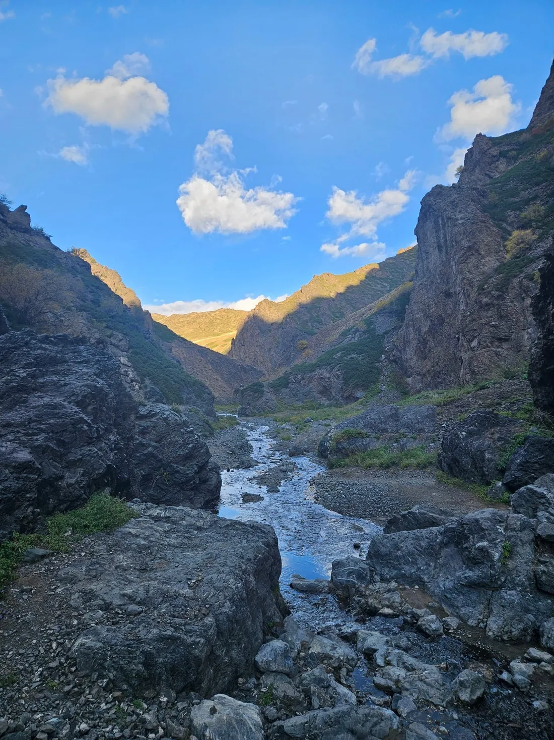 A stream running between dark rocks through the Yolyn Am gorge